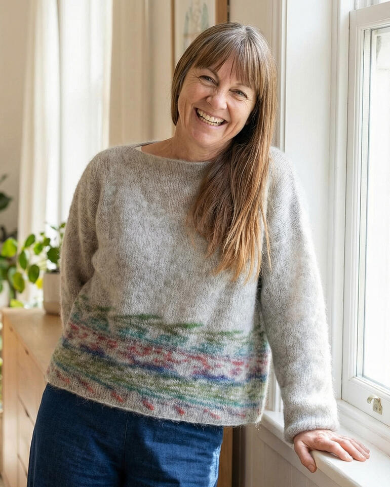 Pullover aus Wonder Sweater mit buntem Muster, lächelnde Frau im Raum.