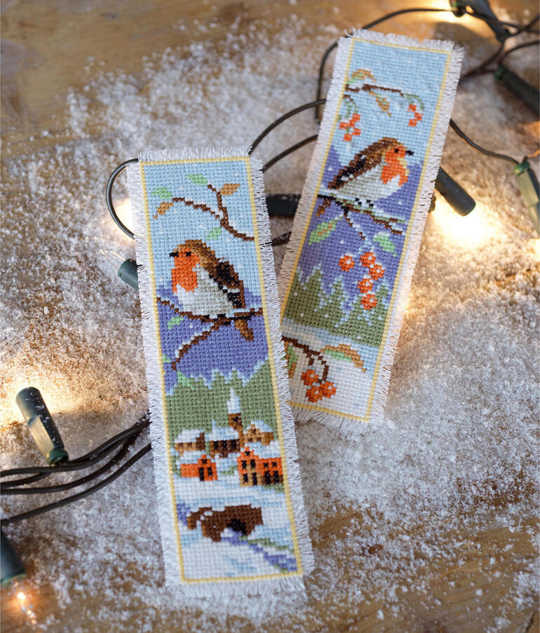 Zwei Lesezeichen mit Rotkehlchen auf winterlichem Hintergrund und Lichtern.