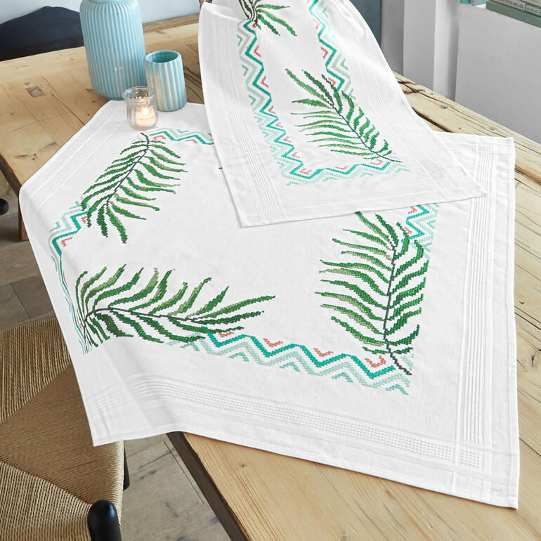 Kreuzstich-Tischwäsche mit Palmenblättern in frischen Farben.