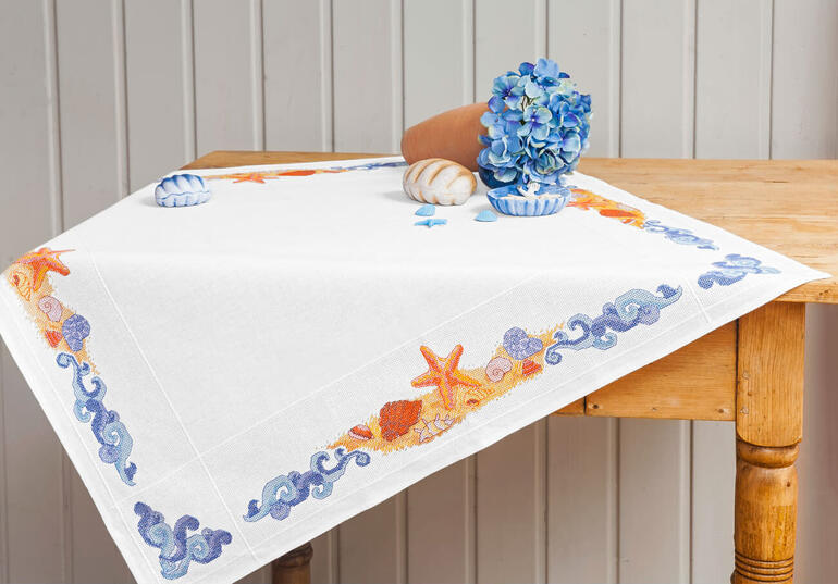 Tischdecke mit maritimen Motiven auf einem Holztisch.