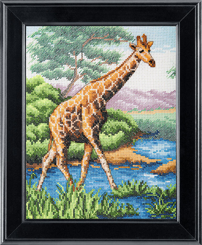 Kreuzstichbild einer Giraffe, die an einem Fluss steht, in einem schwarzen Rahmen.