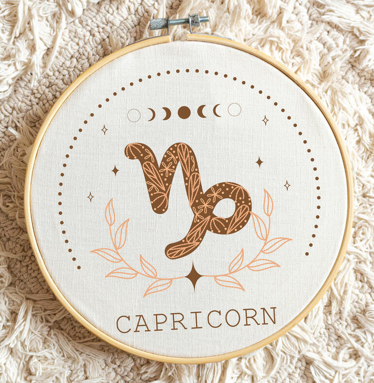 Minimalistische Stickerei des Sternzeichens Steinbock mit floralen Motiven.