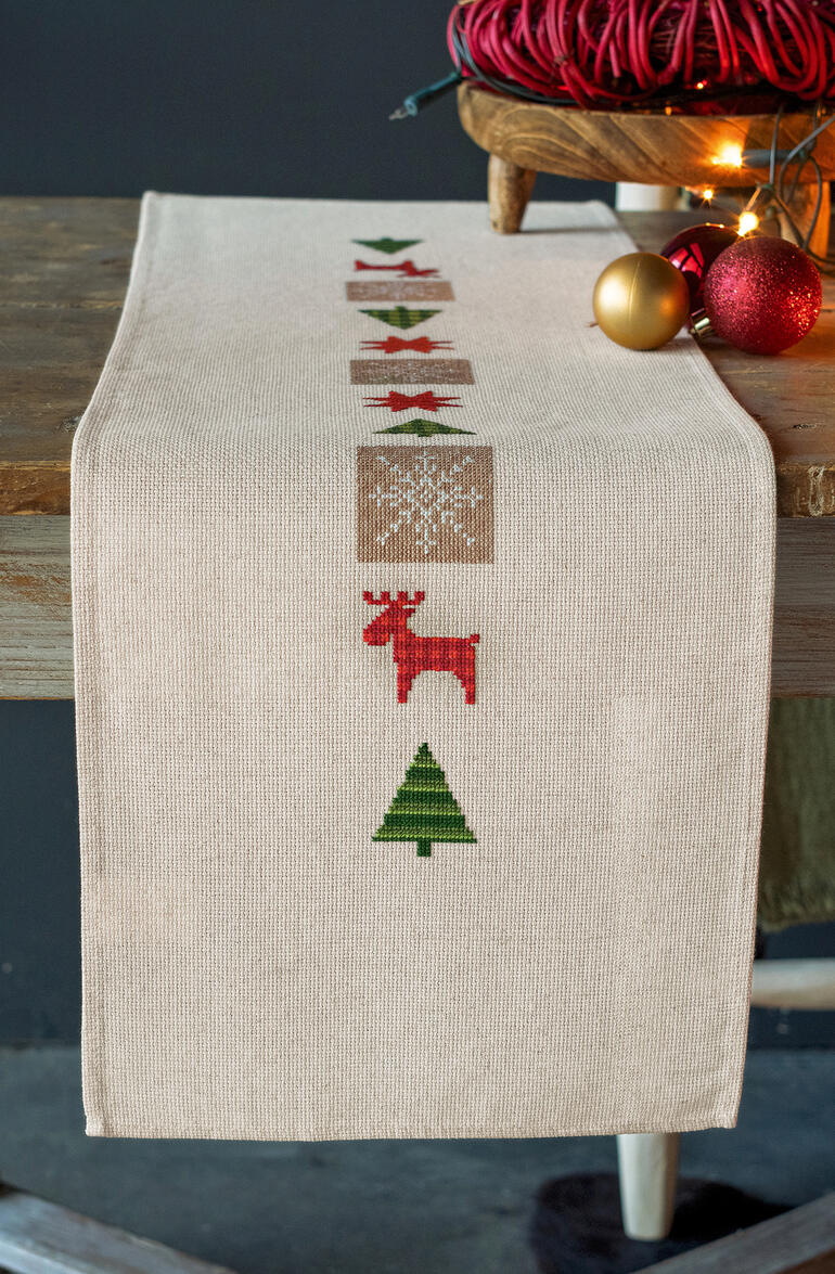 Tischläufer mit weihnachtlichen Symbolen wie Rentieren und Sternen.