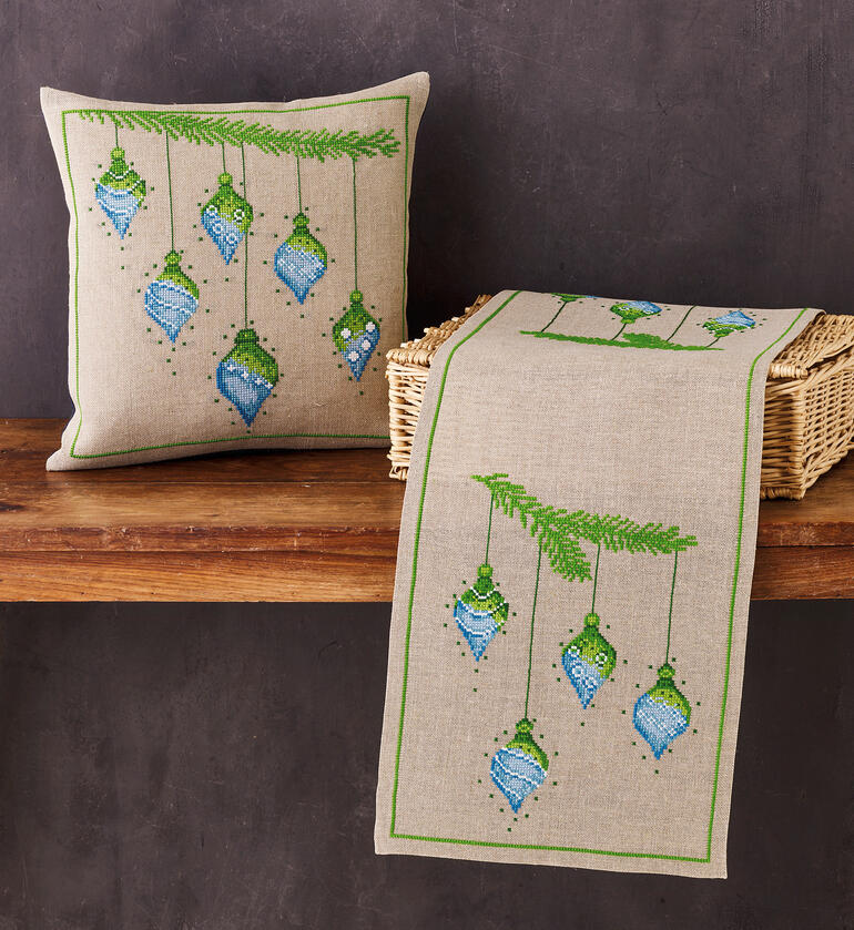 Ensemble aus Kissen und Tischläufer mit Weihnachtskugeln.